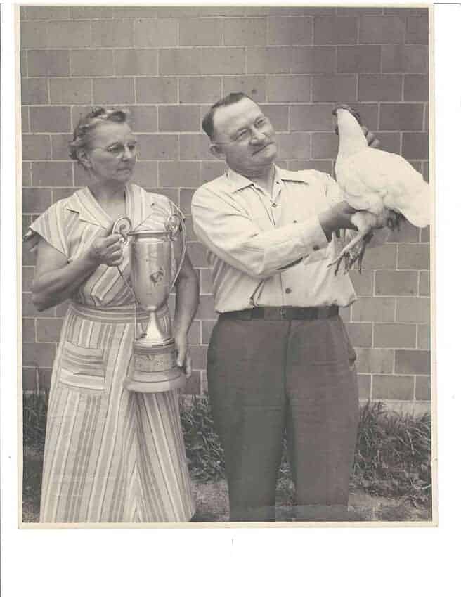 Woman holding a trophy and a man holding a chicken